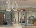 sala obsługi klienta, na pierwszym planie postawione na blacie dwa srebrne balony tworzące liczbę 10 i kosz z jabłkami